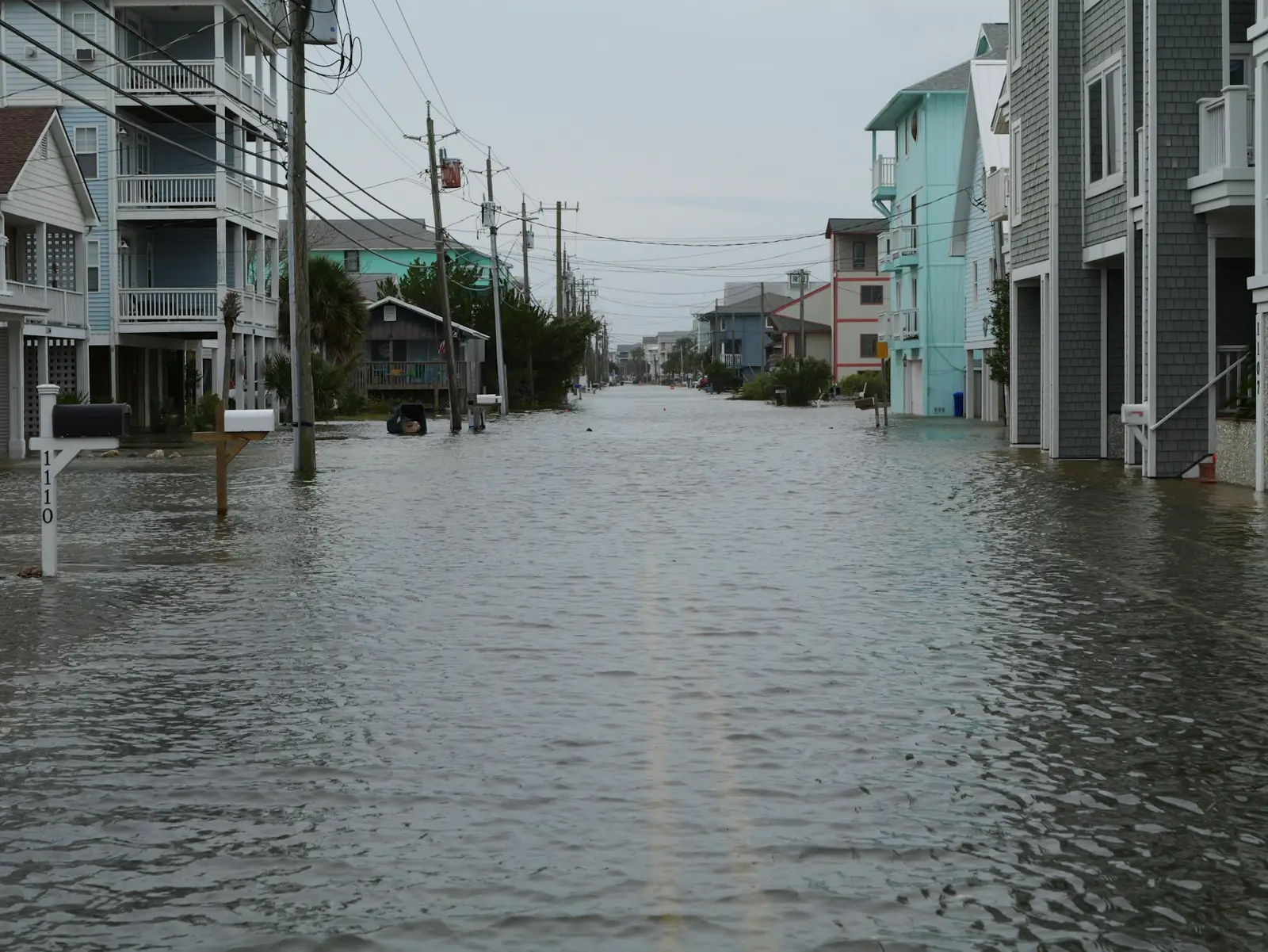 A residential street of raised beach houses covered by tidal floodwater