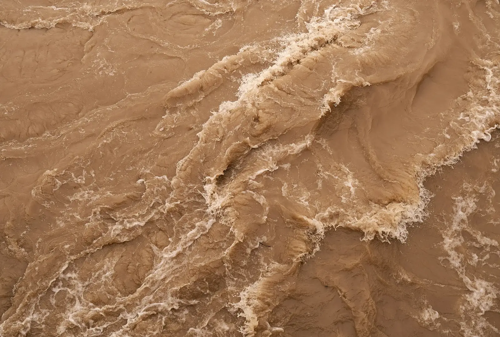 Close-up of fast-moving, muddy brown floodwater