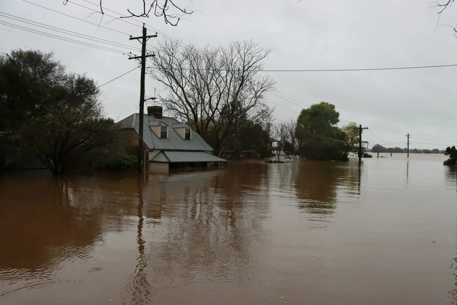 A house with floodwater rising around it under a grey sky